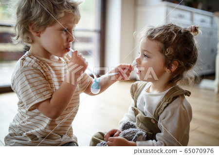 Two small children brother and sister at home, playing with nasal aspirator. 65070976