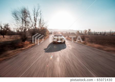 Green sedan car driving on the highway , front view under the ray of sun 65071430