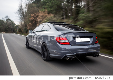 Blue cabriolet with red xenon lights on the forest drive, back view 65071723