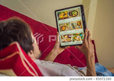 man orders food for lunch online using Tablet 65072160