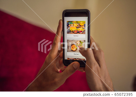 man orders food for lunch online using smartphone man orders food for lunch online using smartphone 65072395