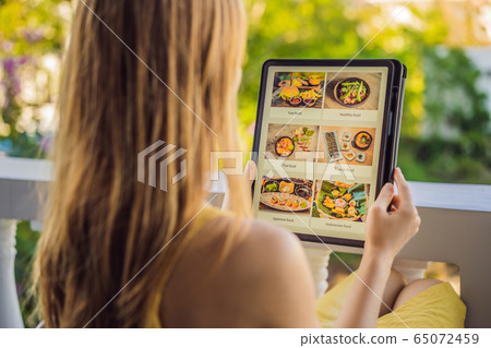 Young woman orders food for lunch online using Tablet 65072459