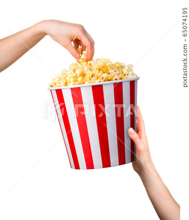 Woman hand taking popcorn from striped bucket Woman hand taking popcorn from striped bucket 65074195