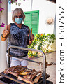 elderly lady cooking on a barbecue with face mask 65075521