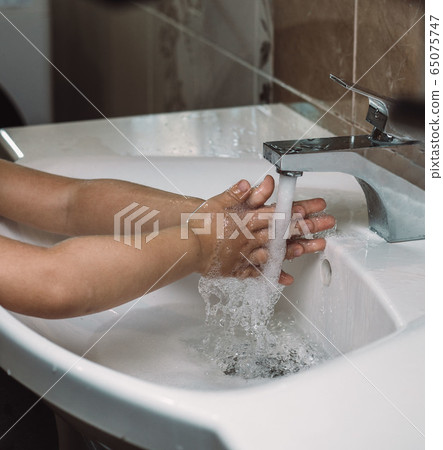 The kid washes his hands with sanitizer 65075747