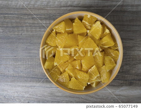 Full bowl of sliced oranges on the wooden table. Full bowl of sliced oranges on the wooden table. 65077149