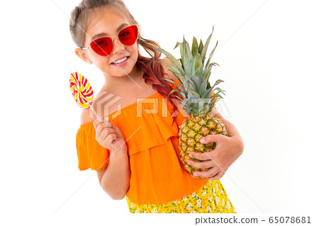 tanned girl with a chupa lollipop and pineapple on a white background 65078681