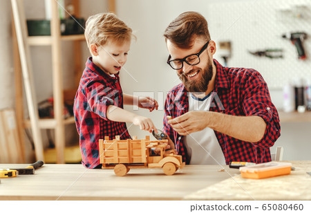 Cheerful man with kid making wooden toys in Cheerful man with kid making wooden toys in 65080460