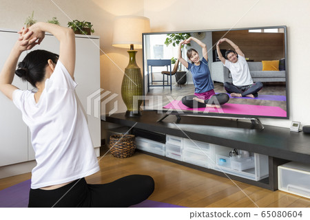 網絡研討會在線瑜伽研討會女人一邊看DVD一邊做瑜伽 網絡研討會在線瑜伽研討會女人一邊看DVD一邊做瑜伽 65080604