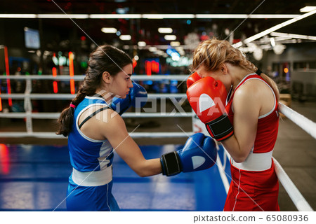 Women in red and blue gloves boxing on the ring 65080936