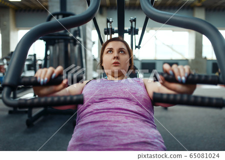 Overweight woman on exercise machine, top view Overweight woman on exercise machine, top view 65081024