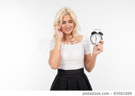 a girl with white hair in a white T-shirt worries that she will be late holding an alarm clock in a girl with white hair in a white T-shirt worries that she will be late holding an alarm clock in 65081889