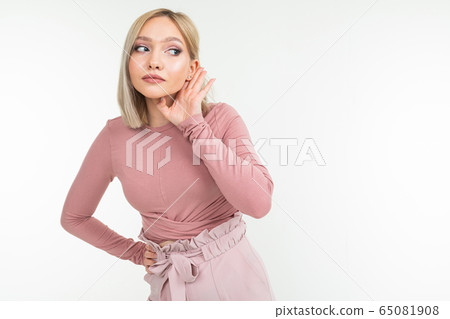 girl with blond haircut overhears a conversation on a white background with copy space girl with blond haircut overhears a conversation on a white background with copy space 65081908