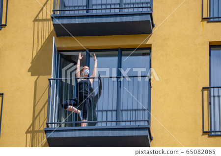 woman in mask practices yoga on balcony of the apartment. Stay home woman in mask practices yoga on balcony of the apartment. Stay home 65082065