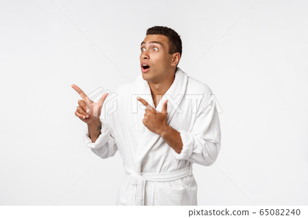 African american guy wearing a bathrobe pointing finger with surprise and happy emotion. Isolated over whtie background. African american guy wearing a bathrobe pointing finger with surprise and happy emotion. Isolated over whtie background. 65082240