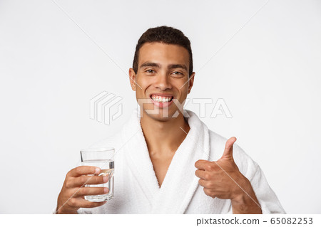 An attractive man drinking a glass of water against white background 65082253
