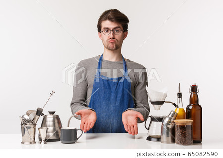 Barista, cafe worker and bartender concept. Portrait of indecisive unsure bearded guy in apron look uncertain, shrugging spread hands sideways frustrated, working , make filter 65082590