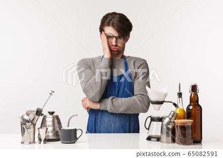 Barista, cafe worker and bartender concept. Portrait of distressed and troubled young male in apron dont know how to make coffee, having troubles learning coffee making, sighing stressed 65082591