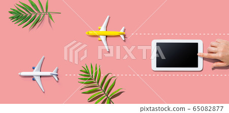 Person using a tablet computer with small airplanes Person using a tablet computer with small airplanes 65082877