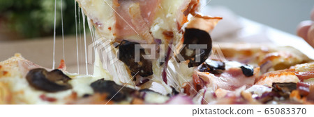 Male hand holding big piece of tasty fresh pizza 65083370