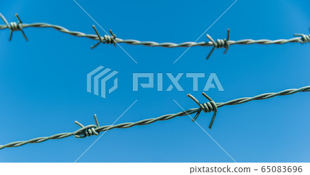 barbed wire with blue sky in the background barbed wire with blue sky in the background 65083696