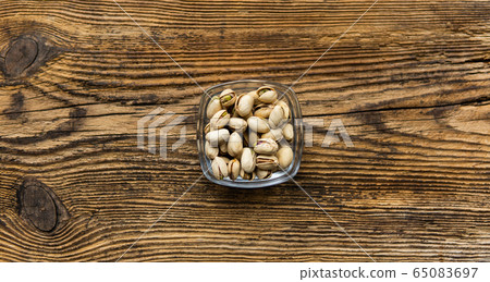 Pistachios in a small plate on a vintage wooden table as a background with a copy space. Pistachio is a healthy vegetarian protein nutritious food. Natural nuts snacks. Pistachios in a small plate on a vintage wooden table as a background with a copy space. Pistachio is a healthy vegetarian protein nutritious food. Natural nuts snacks. 65083697