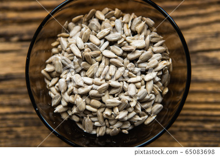 Sunflower seeds in a small plate on the wooden vintage table. Healthy vegetarian protein nutritious food. Sunflower seed on rustic old wood. Sunflower seeds in a small plate on the wooden vintage table. Healthy vegetarian protein nutritious food. Sunflower seed on rustic old wood. 65083698
