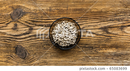 Sunflower seeds in a small plate on the wooden vintage table. Healthy vegetarian protein nutritious food. Sunflower seed on rustic old wood. Sunflower seeds in a small plate on the wooden vintage table. Healthy vegetarian protein nutritious food. Sunflower seed on rustic old wood. 65083699