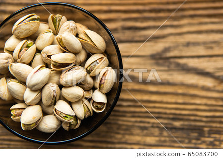 Pistachios in a small plate on a vintage wooden table as a background with a copy space. Pistachio is a healthy vegetarian protein nutritious food. Natural nuts snacks. Pistachios in a small plate on a vintage wooden table as a background with a copy space. Pistachio is a healthy vegetarian protein nutritious food. Natural nuts snacks. 65083700