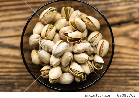 Pistachios in a small plate on a vintage wooden table as a background with a copy space. Pistachio is a healthy vegetarian protein nutritious food. Natural nuts snacks. Pistachios in a small plate on a vintage wooden table as a background with a copy space. Pistachio is a healthy vegetarian protein nutritious food. Natural nuts snacks. 65083702