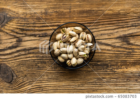 Pistachios in a small plate on a vintage wooden table as a background with a copy space. Pistachio is a healthy vegetarian protein nutritious food. Natural nuts snacks. Pistachios in a small plate on a vintage wooden table as a background with a copy space. Pistachio is a healthy vegetarian protein nutritious food. Natural nuts snacks. 65083703