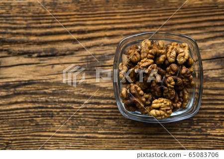 Walnut in a small plate on a vintage wooden table as a background. Walnuts is a healthy vegetarian protein nutritious food. Natural nuts snacks. Walnut in a small plate on a vintage wooden table as a background. Walnuts is a healthy vegetarian protein nutritious food. Natural nuts snacks. 65083706