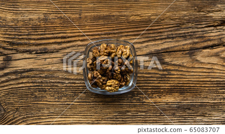 Walnut in a small plate on a vintage wooden table as a background. Walnuts is a healthy vegetarian protein nutritious food. Natural nuts snacks. Walnut in a small plate on a vintage wooden table as a background. Walnuts is a healthy vegetarian protein nutritious food. Natural nuts snacks. 65083707