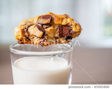 Chewy chocolate chip soft cookie on cup of milk Chewy chocolate chip soft cookie on cup of milk 65083800