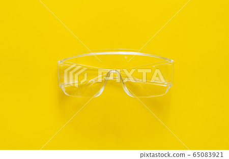 Protective glasses lying on a yellow background. 65083921