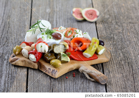 A selection of typical Greek appetizers on a wooden cutting board A selection of typical Greek appetizers on a wooden cutting board 65085201