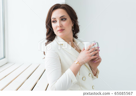 Woman holding a white cup of coffee. With a beautiful manicure. Drink, fashion, morning Woman holding a white cup of coffee. With a beautiful manicure. Drink, fashion, morning 65085567