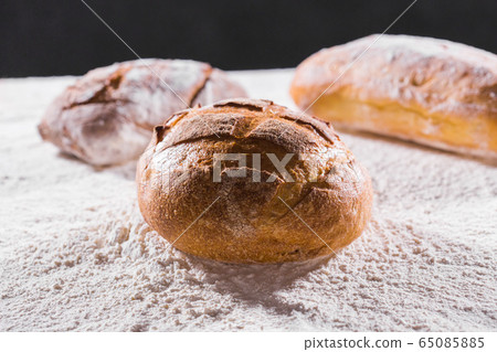 Fresh bread on table close-up in flour placer. Fresh bread on the kitchen table. The healthy eating and traditional bakery concept. Rustic style Fresh bread on table close-up in flour placer. Fresh bread on the kitchen table. The healthy eating and traditional bakery concept. Rustic style 65085885
