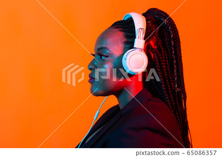 Neon portrait of young black woman listen to music in headphones. 65086357