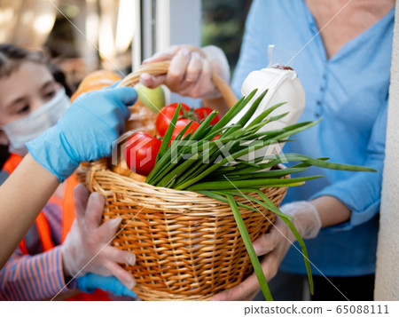 Teenage girls activists from a youth organization deliver food to a woman who is in self-isolation. Teenage girls activists from a youth organization deliver food to a woman who is in self-isolation. 65088111
