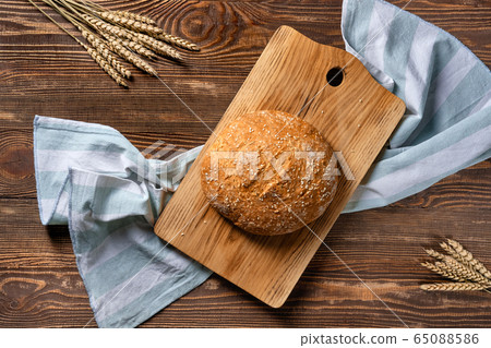 Overhead view of homemade wheat bread on wooden cutting board 65088586