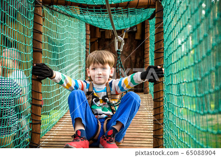 Cute boy overcomes obstacles in rope adventure Cute boy overcomes obstacles in rope adventure 65088904