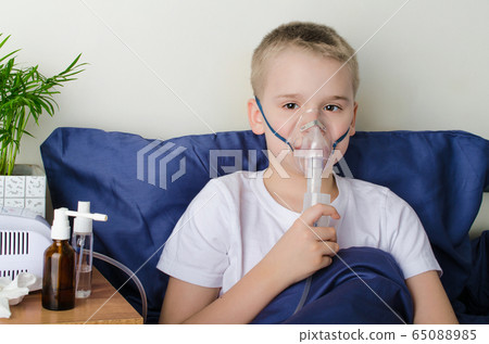 Sick boy breathing through inhaler mask. Use of nebulizer and inhaler Sick boy breathing through inhaler mask. Use of nebulizer and inhaler 65088985