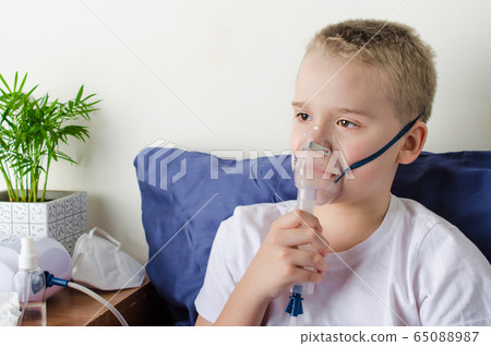 Sick boy breathing through inhaler mask. Use of nebulizer and inhaler Sick boy breathing through inhaler mask. Use of nebulizer and inhaler 65088987