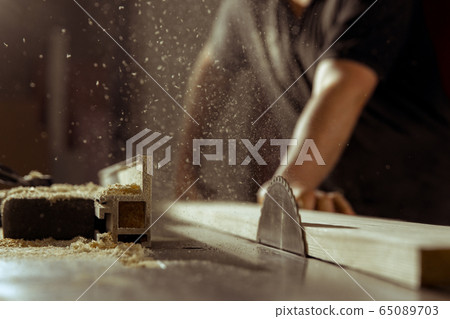 A man cuts wood on a circular saw in a joinery A man cuts wood on a circular saw in a joinery 65089703