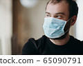 Portrait of man wearing a protective medical face mask to prevent infection of coronavirus. 65090791