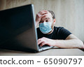 Coronavirus, an adult male with a beard works at a laptop. Protective respiratory mask. 65090797