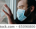 Coronavirus. Sick man of corona virus looking through the window and wearing mask protection. 65090800