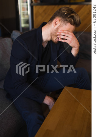 successful beautiful young man blond is located in a modern loft room, hookah successful beautiful young man blond is located in a modern loft room, hookah 65091248