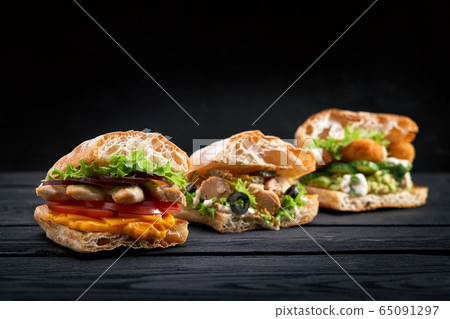 Closeup three different Appetizing sandwiches or burgers on wooden background Closeup three different Appetizing sandwiches or burgers on wooden background 65091297